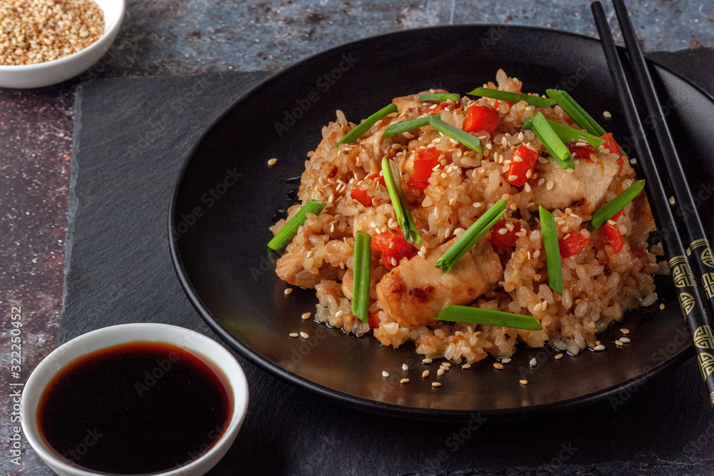 Tori chahan fried Japanese rice with vegetables and chicken in soy sauce in a black plate on a serving board Tori chahan fried Japanese rice with vegetables and chicken in soy sauce in a black plate on a serving board