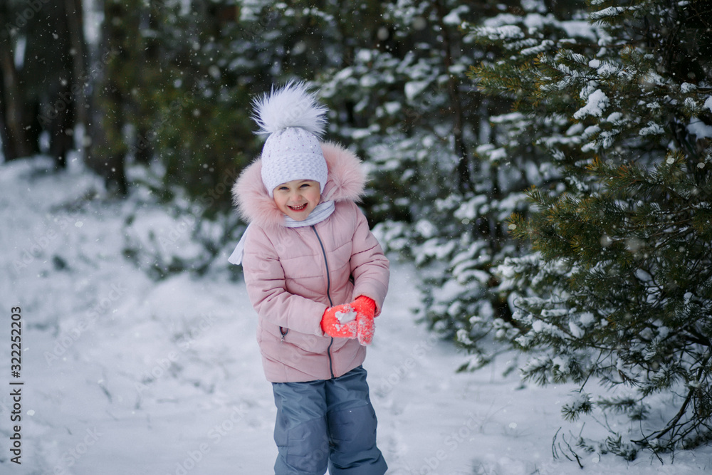 little girl plays snowballs outdoors in winter