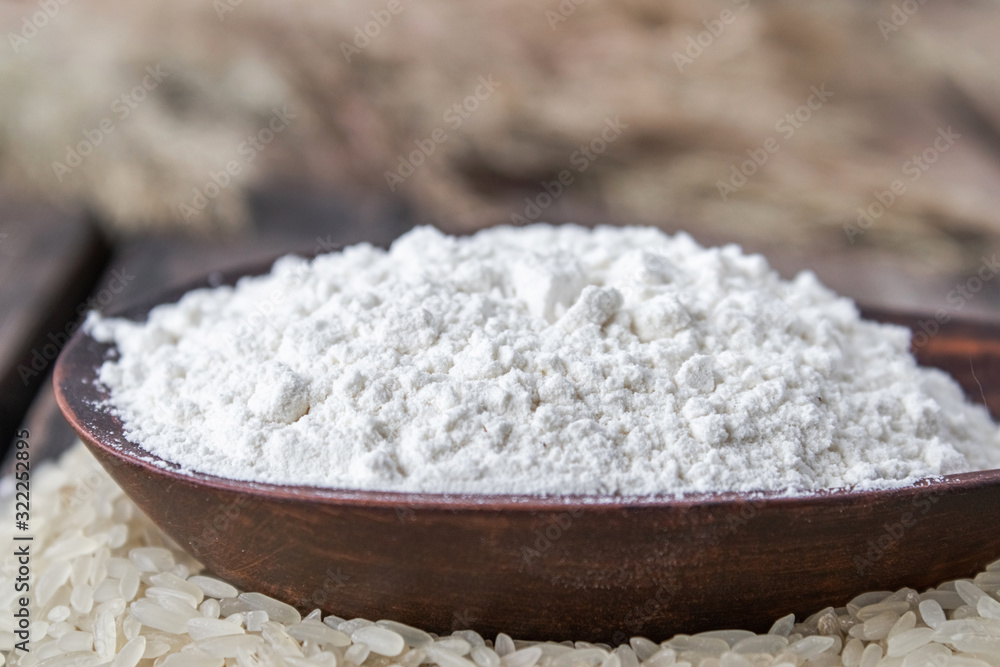 Rice flour in a bowl on a pile of white rice on old boards. Rice flour in a bowl on a pile of white rice on old boards.