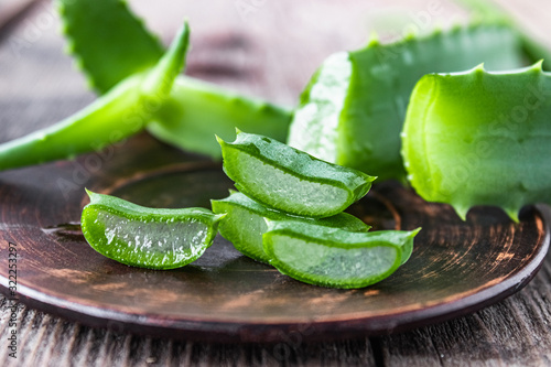 Slices of aloe vera in a bowl on a wooden table.