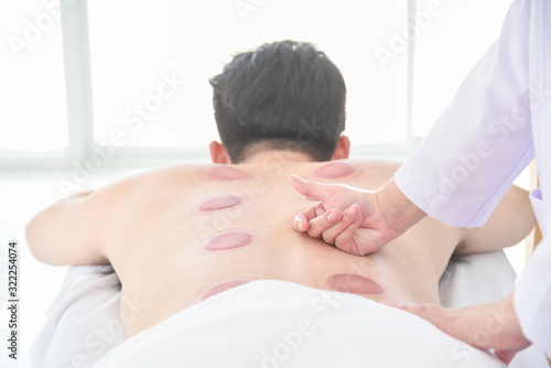 Therapist doing Tui na massage for her patient after cupping therapy finished ,Chinese alternative medicine. photo