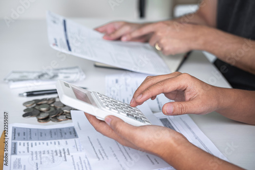 Images of Husband and wife using calculator to calculating expenditure receipt bills of various activity cost and expenses in home office and written make report to plan of spent in future