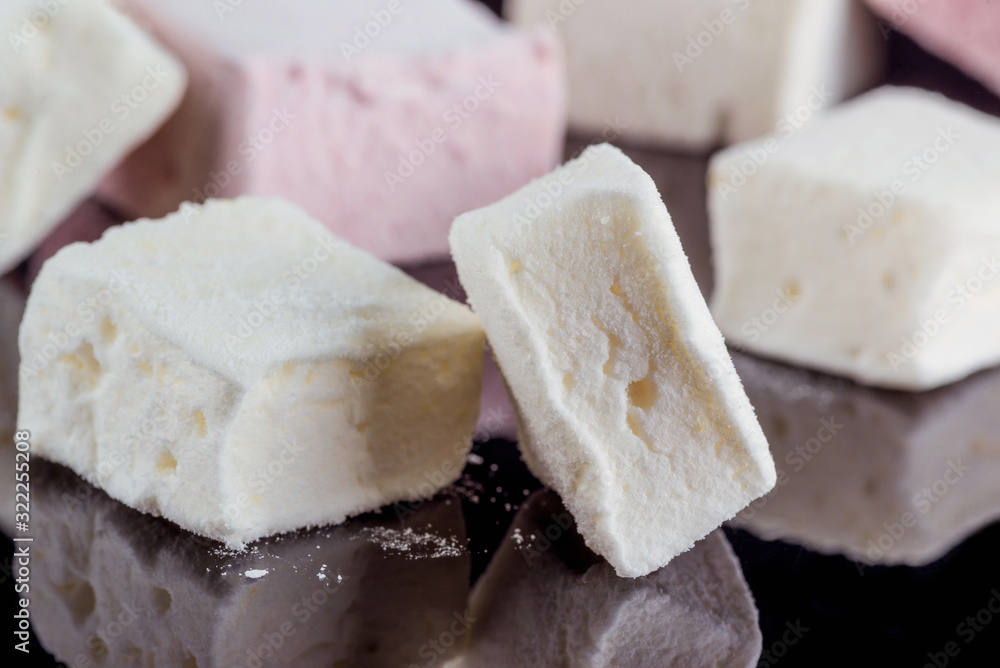 Beautiful handmade pink and white marshmallows on a black mirror surface. Close-up.