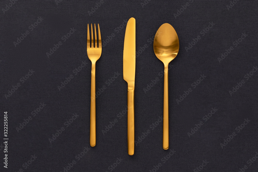 Golden Fork, knife, and spoon on the black table cloths. Golden Fork, knife, and spoon on the black table cloths.