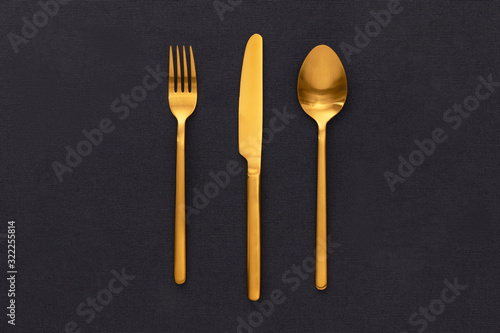 Golden Fork, knife, and spoon on the black table cloths.