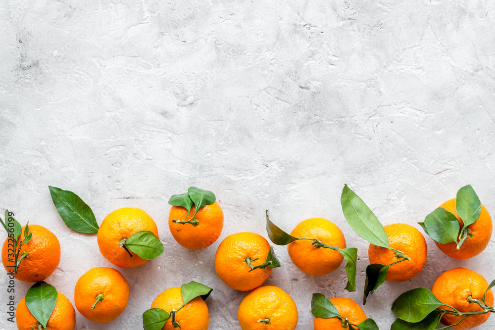 Tangerines with leaves frame on grey background top-down copy space