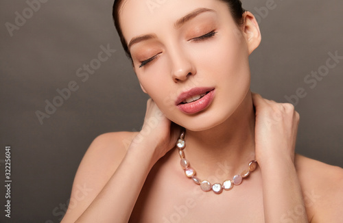 Sensual young brown-haired woman with pearl beads.