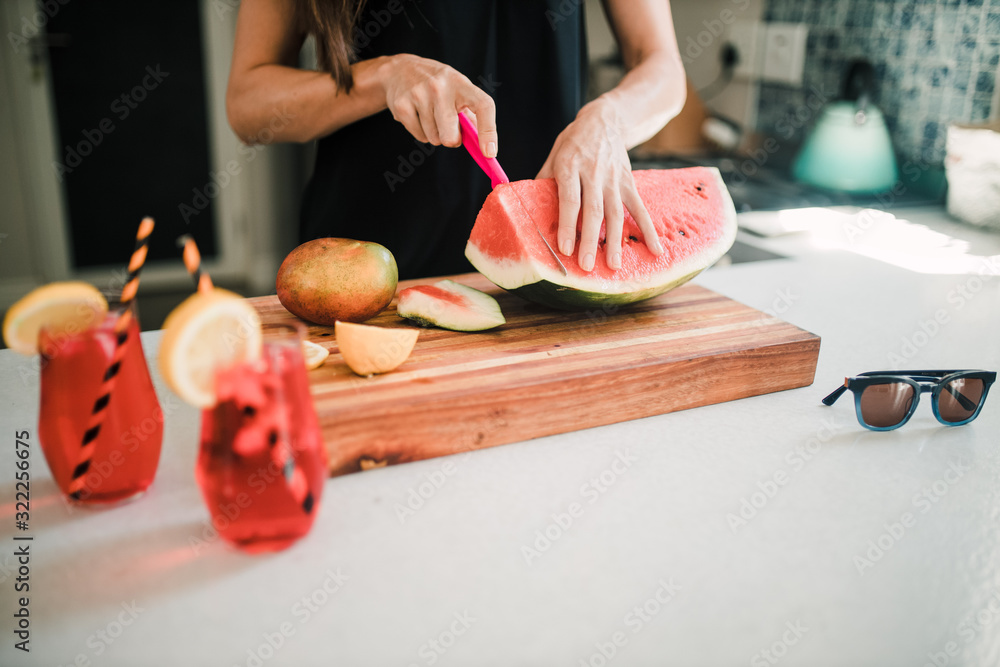 Beautiful woman cutting a watermelon in the kitchen Beautiful woman cutting a watermelon in the kitchen