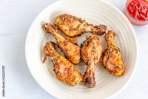 Baked Chicken Legs with Tomato Ketchup on a White Background, Top View Close Up Photo.