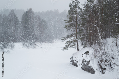 Blurred defocused photo of winter landscape. Forest, valley and falling snow
