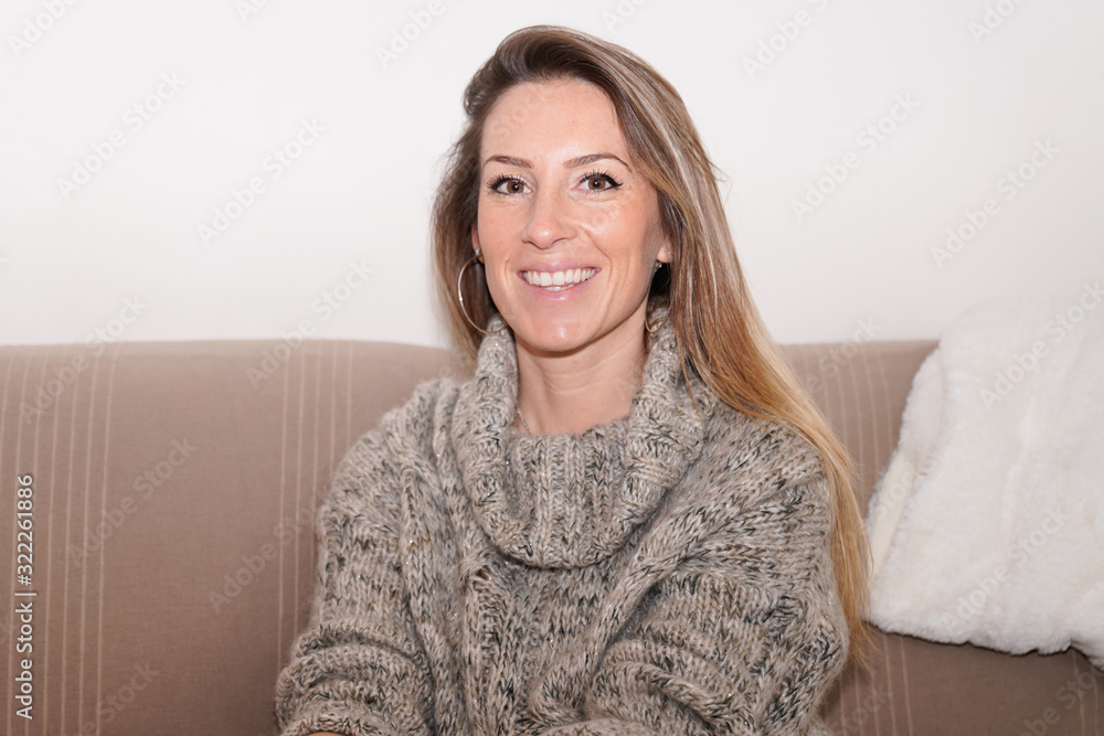 Smiling young beautiful blonde woman sit on home couch Smiling young beautiful blonde woman sit on home couch