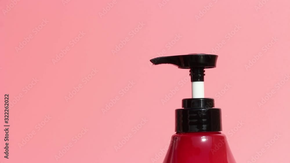 Female hands squeeze soap with a dispenser close up, pink background Female hands squeeze soap with a dispenser close up, pink background