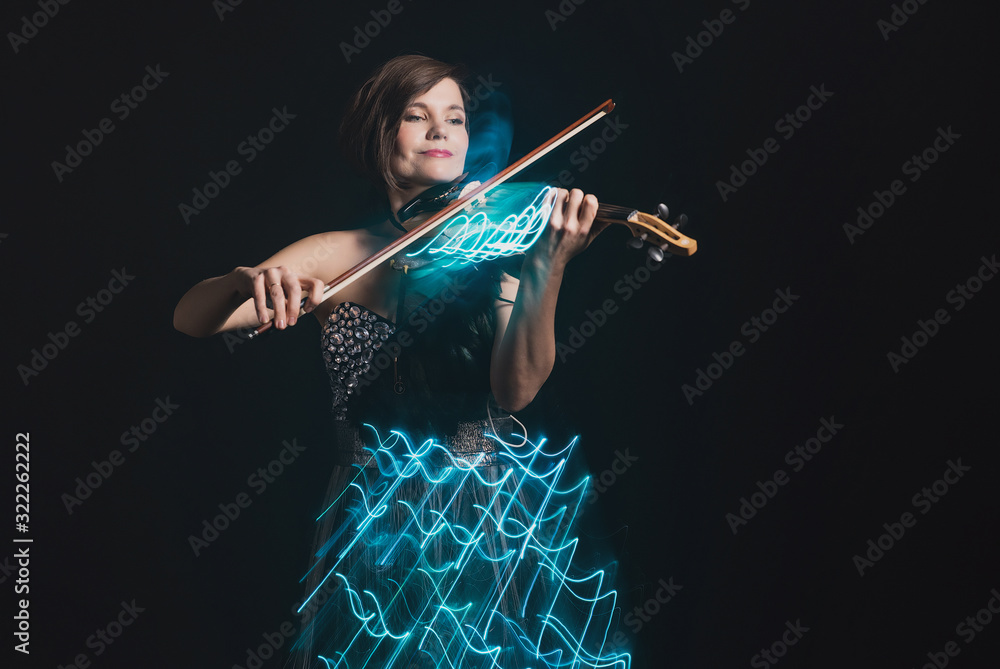 A woman plays the violin on the background of abstract light strips, visualization of musical compositions