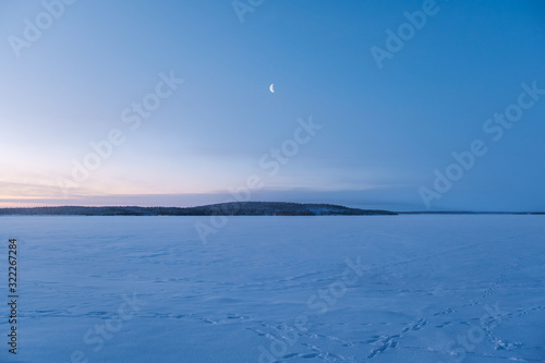 Winter landscape in Russia. New moon rising over forest