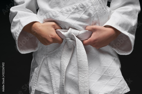 hands closeup - teenager dressed in martial arts clothing posing on a dark gray background, a sports concept