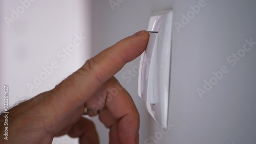 Businessman Hand Pushing On the Light Switch from Office Room Wall