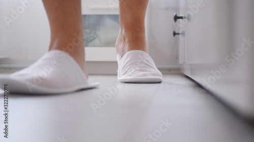 Man in the Bedroom with White Slippers in His Foots, Image with a Person Walking with Slippers in a Hotel Room