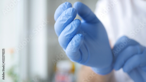 Nurse in a Hospital Room Putting on Her Hand's Blue Rubber Protection Gloves