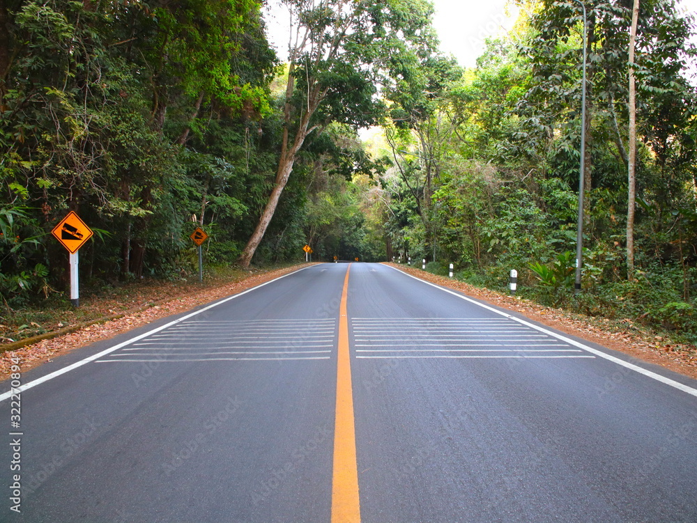 Fototapeta premium Empty Road with an endless yellow line in the mountains of Chiangmai Thailand surrounded by dense forests