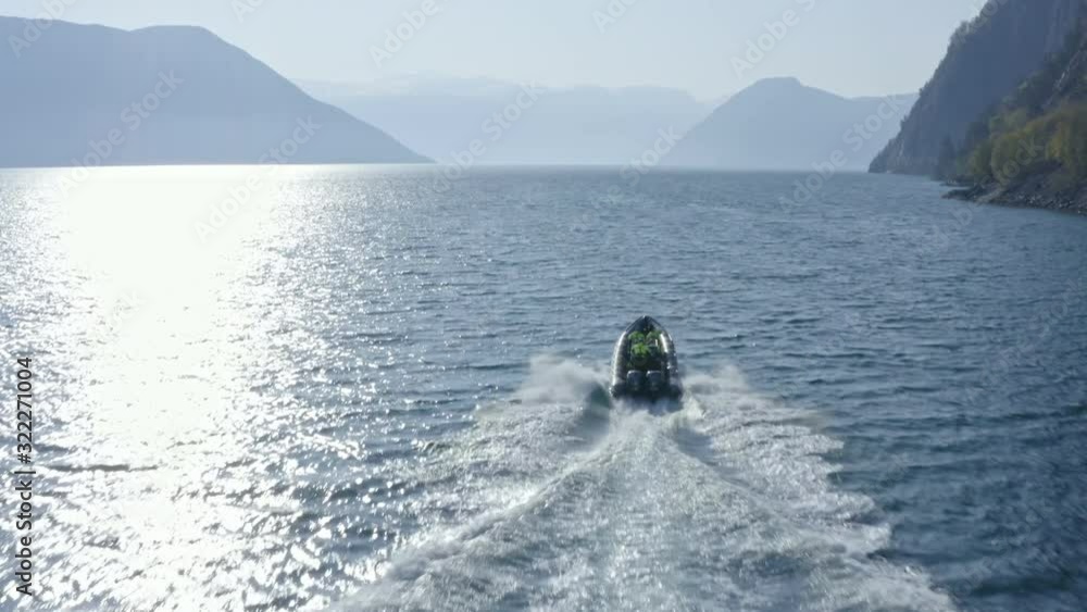 Aerial drone reveal in a Fjord following a boat in Norway with on a cold sunny day with view of mountains, Norway, Scandinavia, norther Europe, fjords.