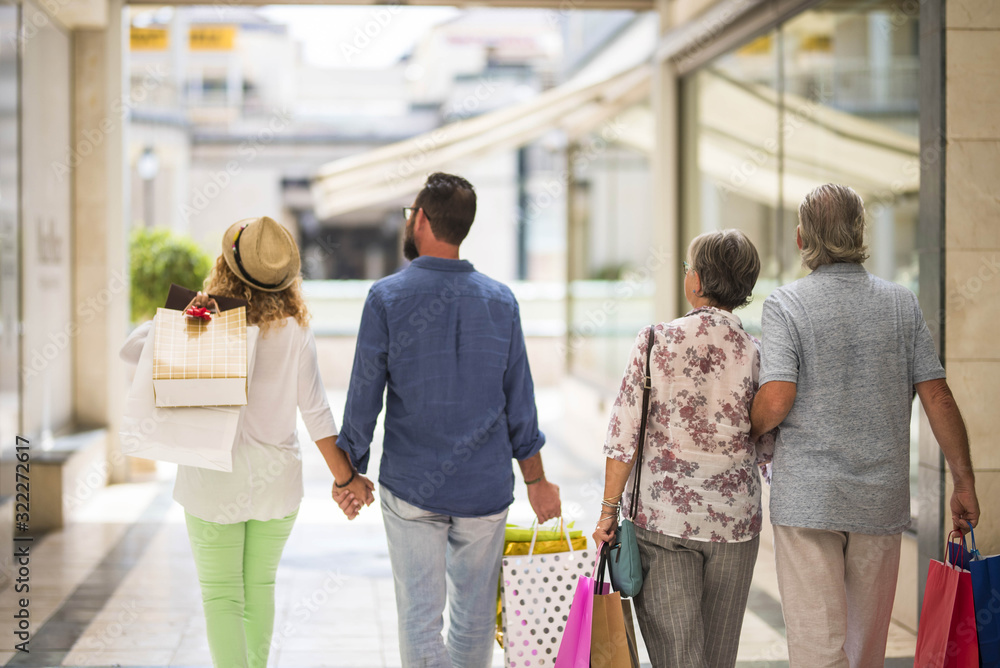 group or family walking together in a mall doing shopping and holding shopping bags - adults and seniors looking at the shops or stores group or family walking together in a mall doing shopping and holding shopping bags - adults and seniors looking at the shops or stores