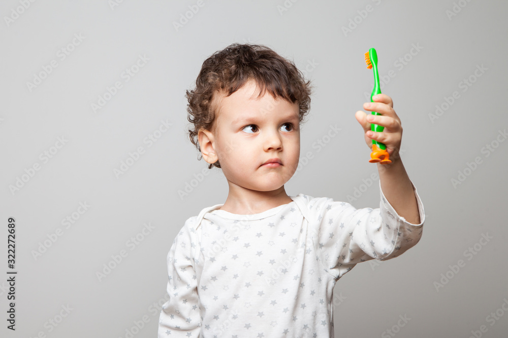 funny little boy, toddler with a toothbrush in his hands. a serious look at the counter. hygiene in the morning and at bedtime