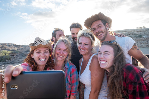 group of seven people having fun together and smiling takinng a selfie looking at the camera - group of friends enjoying together