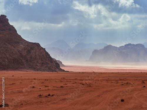 Fototapeta Naklejka Na Ścianę i Meble -  Beautiful Scenery Scenic Panoramic View Red Sand Desert and Ancient Sandstone Mountains Landscape in Wadi Rum, Jordan during a Sandstorm