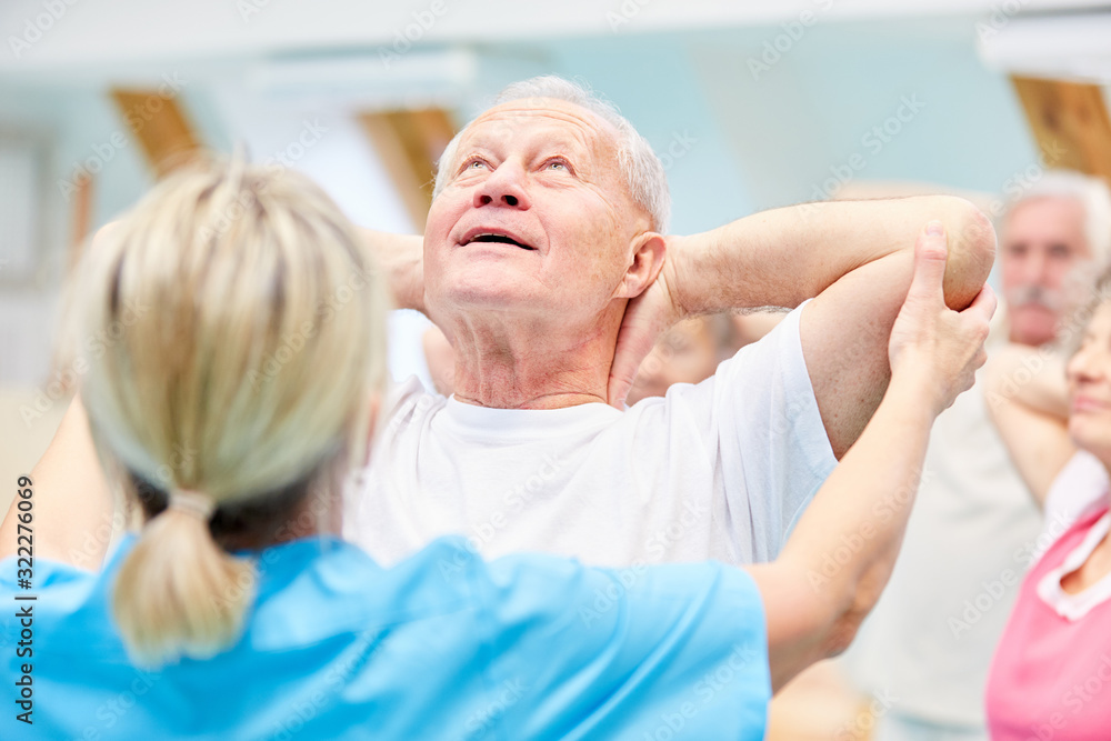 Obraz premium Trainer supervises senior in back exercises