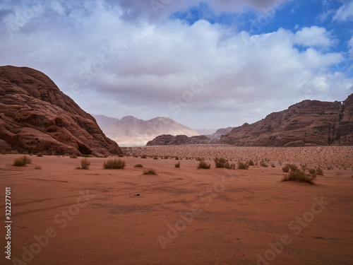 Fototapeta Naklejka Na Ścianę i Meble -  Beautiful Scenery Scenic Panoramic View Red Sand Desert and Ancient Sandstone Mountains Landscape in Wadi Rum, Jordan during a Sandstorm