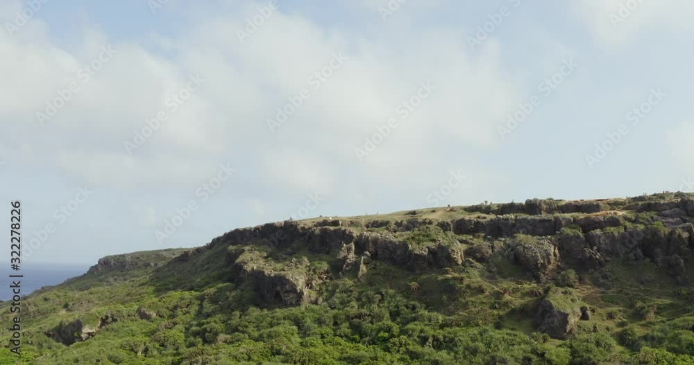 The Peak View Of A Rocky Mountain In Kenting National Park With Green Grassland Under The Bright Cloudy Sky - Aerial Shot The Peak View Of A Rocky Mountain In Kenting National Park With Green Grassland Under The Bright Cloudy Sky - Aerial Shot