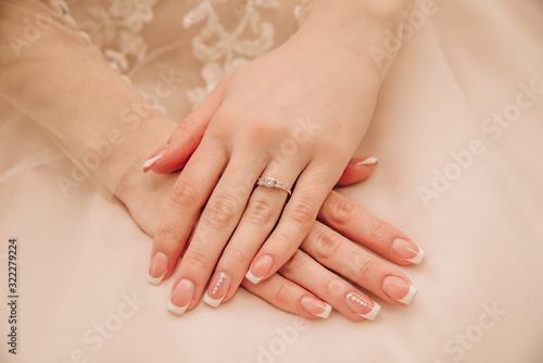 hands of a young girl with beautiful manicure lie on a dress