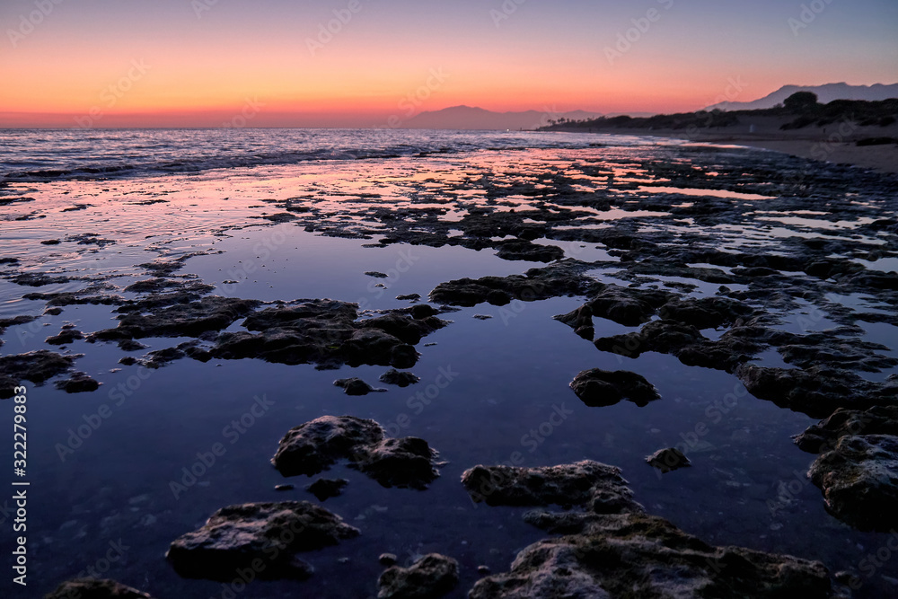 Beach rocks in low tide at the sunset in Marbella Cabopino beach Beach rocks in low tide at the sunset in Marbella Cabopino beach