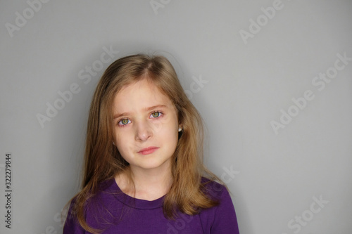 Close-up studio portrait of unhappy beautiful little girl with tears.