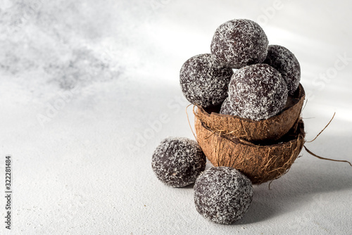 Homemade healthy protein energy balls in a coconut bowl with dried apricots, raisins, walnuts, almonds and coconut. Healthy sweet food.