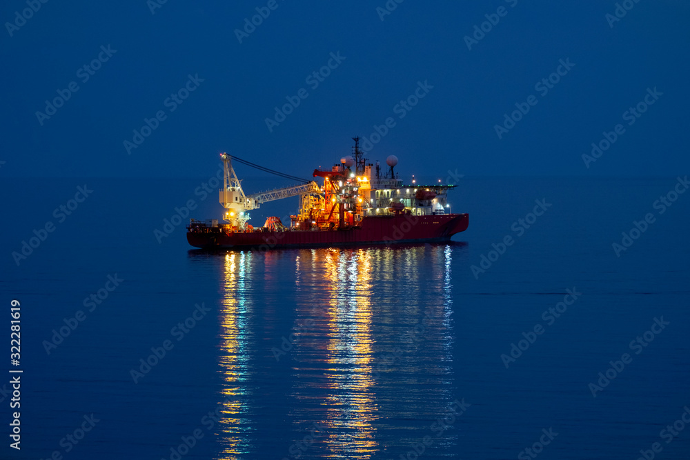 Offshore ship crane with reflections at night in the sea 