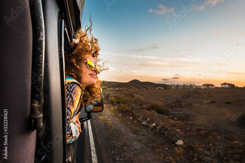 Fotografia beautiful caucasian young woman travel outside the car with wind in the curly ha