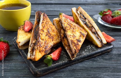 Sweet french toasts with banana, chocolate, strawberries on a wooden background. Tasty breakfast. Top view