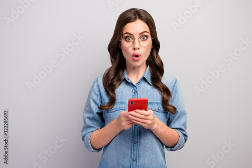 Photo of beautiful business lady browsing telephone check followers addicted user open mouth read unbelievable news wear specs casual jeans denim shirt isolated grey color background