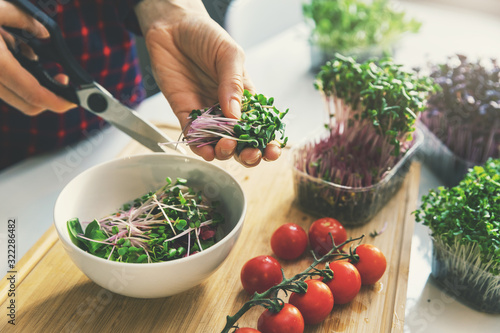 woman prepare fresh raw vegan salad from microgreens and vegetables