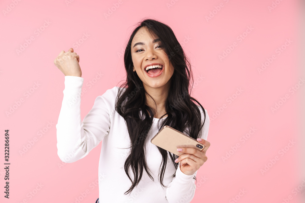 Image of young asian woman holding cellphone and playing video games Image of young asian woman holding cellphone and playing video games