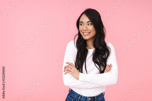 Image of young brunette asian woman standing with arms crossed