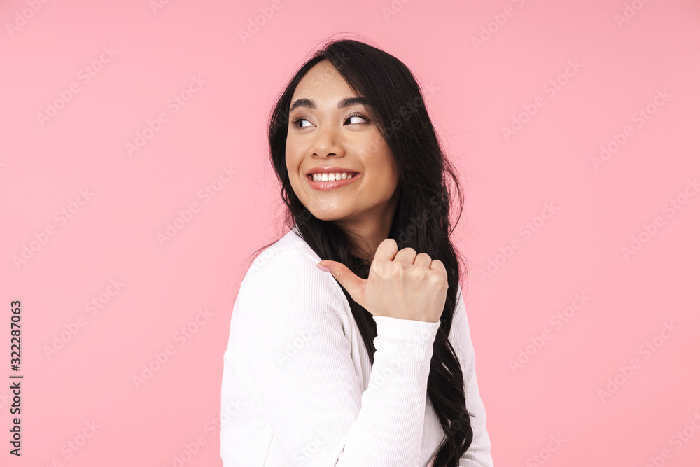 Image of young brunette asian woman smiling and pointing fingers aside Image of young brunette asian woman smiling and pointing fingers aside