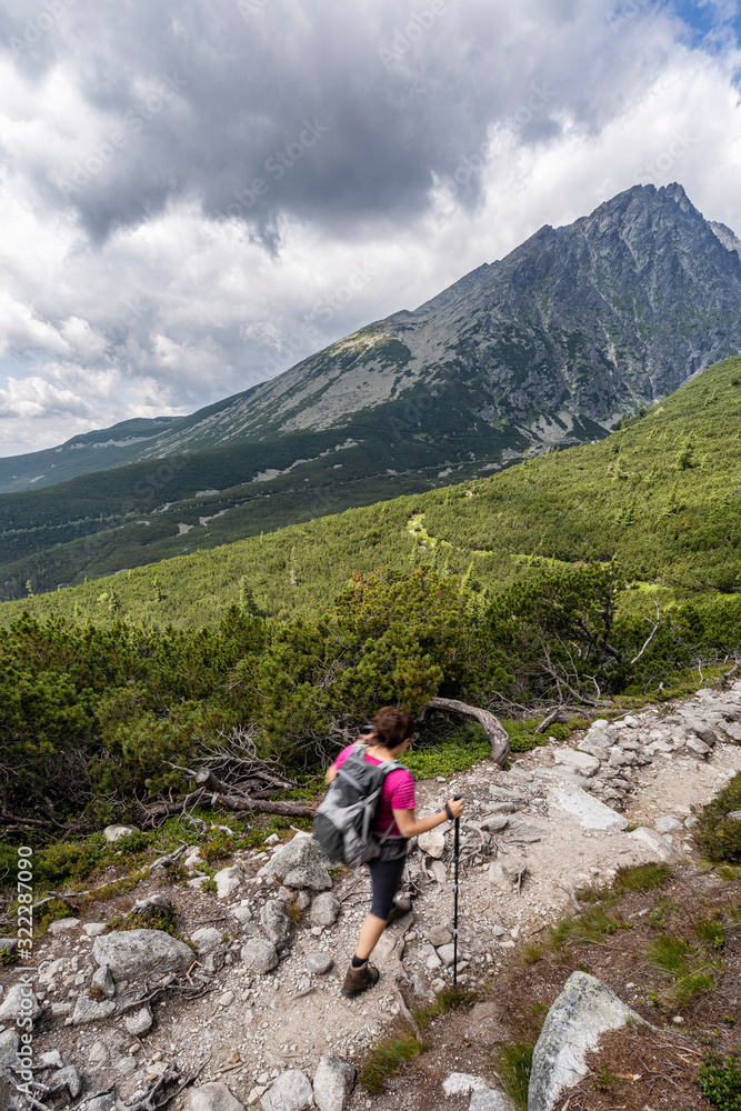 Young woman on a mountain terrain trail. Hiking in High Tatras National Park, Slovakia.
