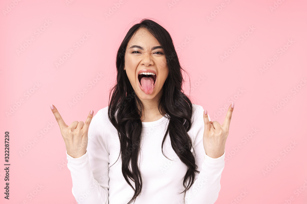 Image of young asian woman having fun and gesturing horn fingers Image of young asian woman having fun and gesturing horn fingers