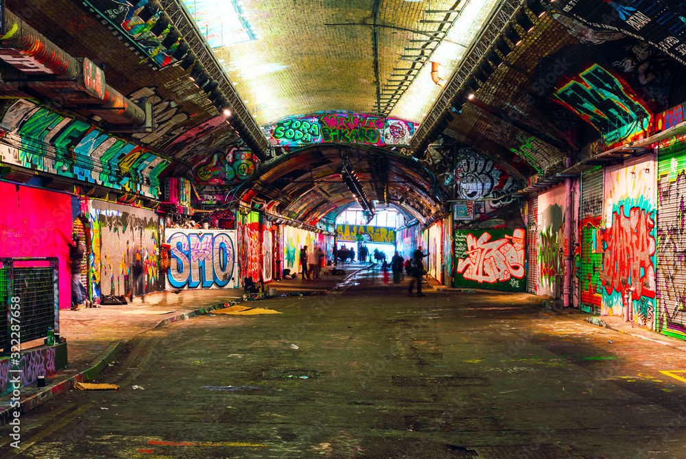 London, UK/Europe; 21/12/2019: Leake Street, underground tunnel with graffiti covered walls in London. Scene with pedestrians and graffiti artists.