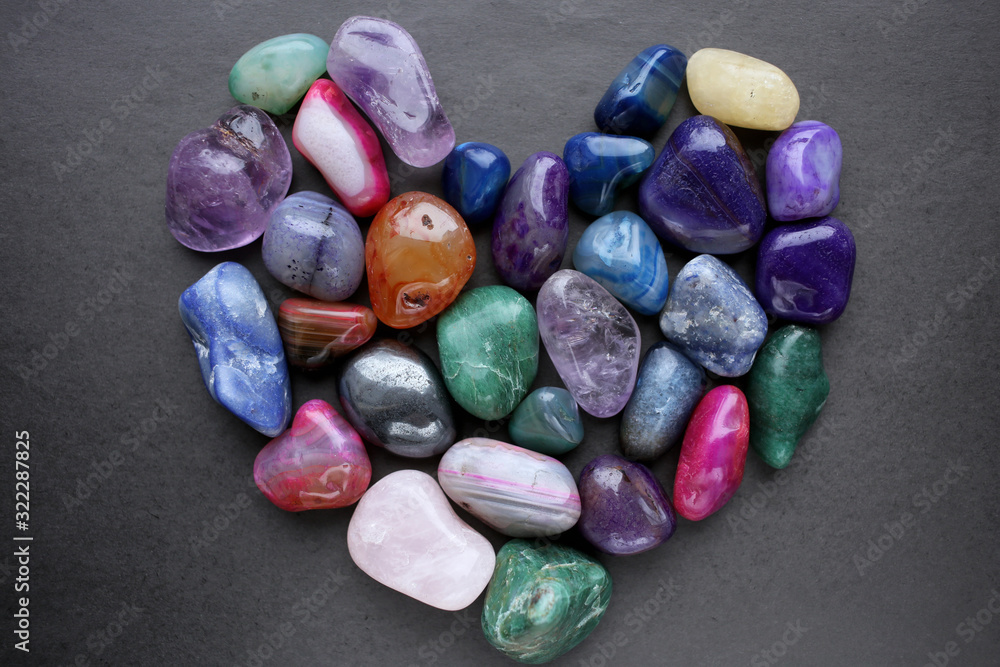 Colored gemstones laid out in the shape of a heart on a black background. Colored gemstones laid out in the shape of a heart on a black background.