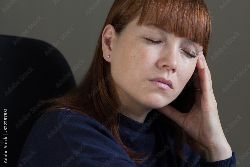 Portrait of middle aged woman holding hand close to temple with close eyes Portrait of middle aged woman holding hand close to temple with close eyes
