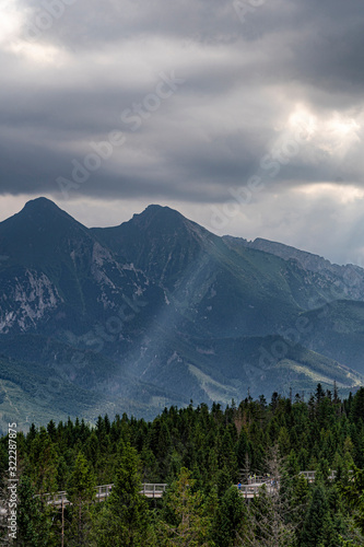 Scenic view of sun rays over mountain landscape. Dramatic summer stormy in High Tatras mountains. Sun rays over hills and valley.