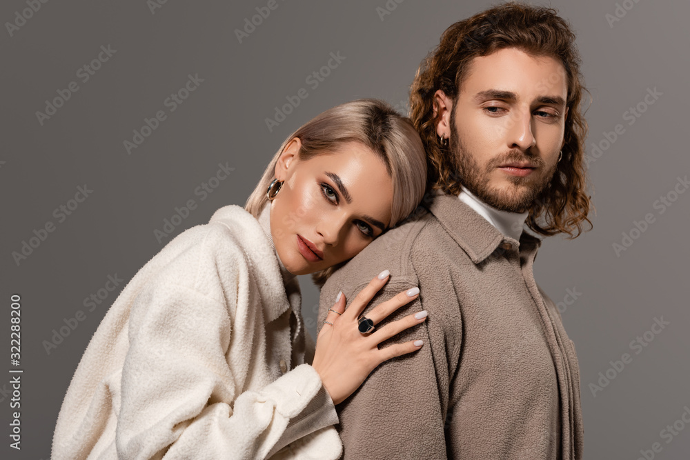 woman in white coat hugging handsome man in shirt isolated on grey